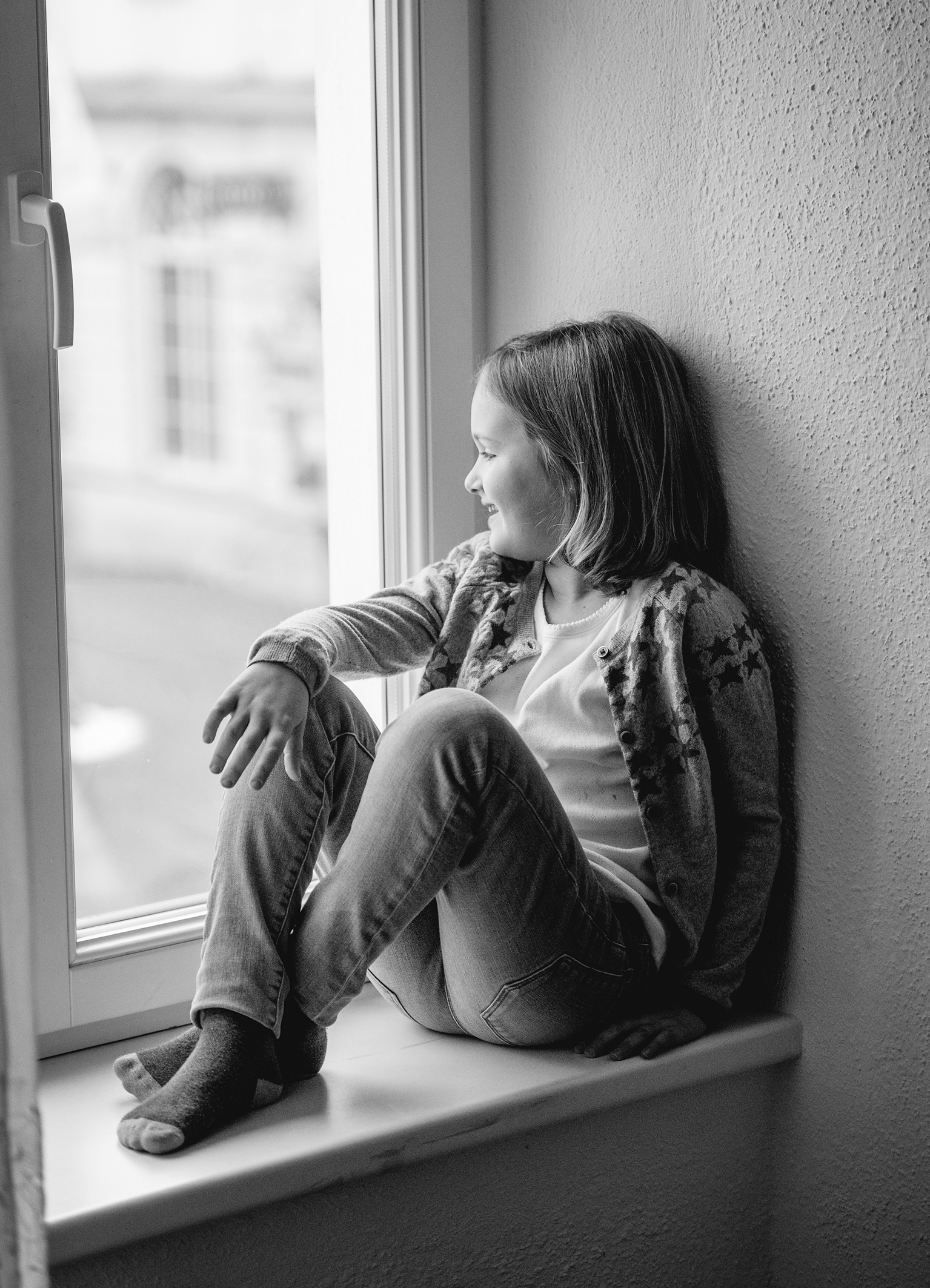 Mädchen sitzt lächelnd am Fenster